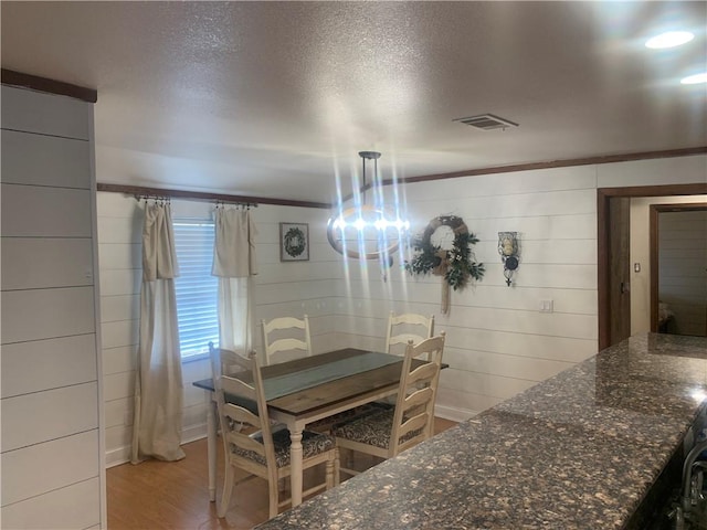 dining area with crown molding, light hardwood / wood-style flooring, and a textured ceiling