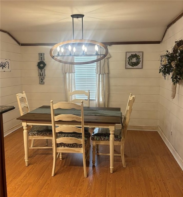 dining area featuring ornamental molding, hardwood / wood-style flooring, and wood walls