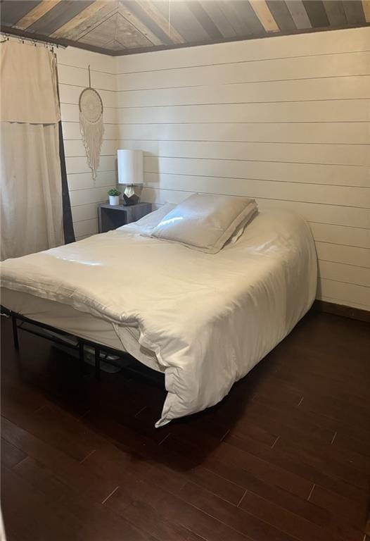 bedroom with dark hardwood / wood-style floors and wooden walls