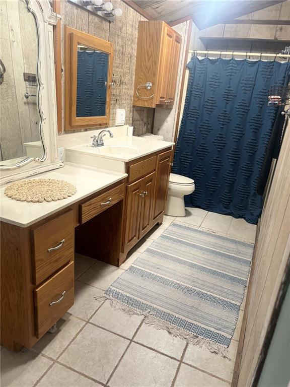 bathroom featuring vanity, toilet, tile patterned floors, and wooden walls