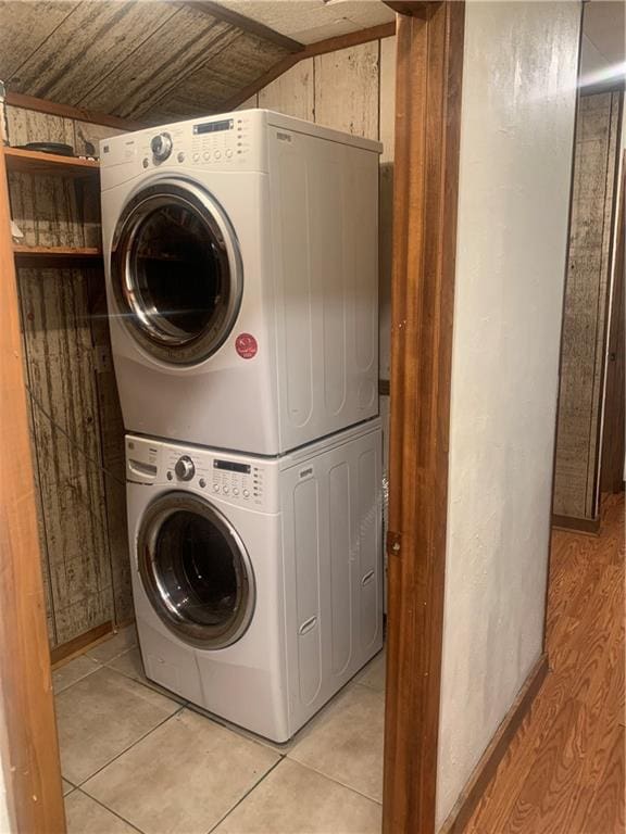 washroom featuring stacked washer and clothes dryer, wooden ceiling, and light tile patterned floors