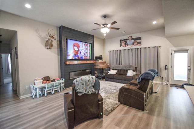 living room featuring hardwood / wood-style flooring, a large fireplace, and ceiling fan