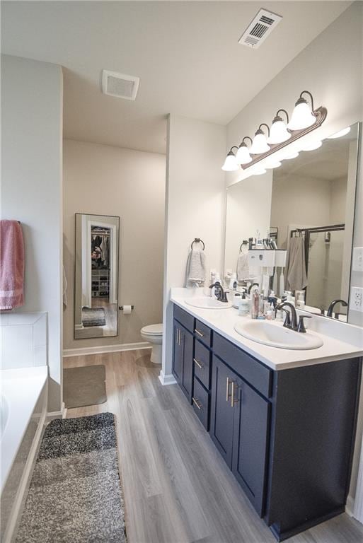 full bathroom with vanity, hardwood / wood-style floors, independent shower and bath, and toilet