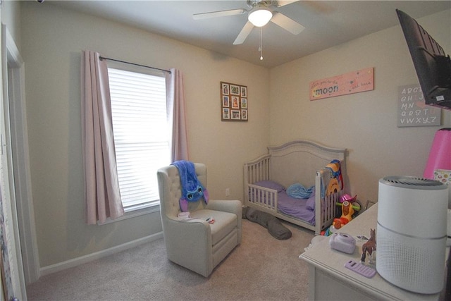 bedroom featuring ceiling fan, light carpet, and a crib