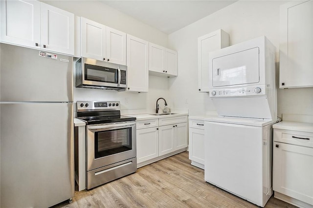 2437 Dumaine St, New Orleans, LA 70119 - kitchen featuring stainless steel appliances, stacked washer and clothes dryer, and white cabinets