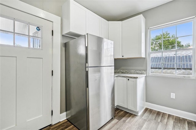 2437 Dumaine St, New Orleans, LA 70119 - kitchen with freestanding refrigerator, light wood-type flooring, and white cabinetry