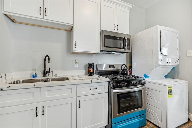 kitchen featuring white cabinetry, sink, stainless steel appliances, light stone counters, and stacked washer and dryer