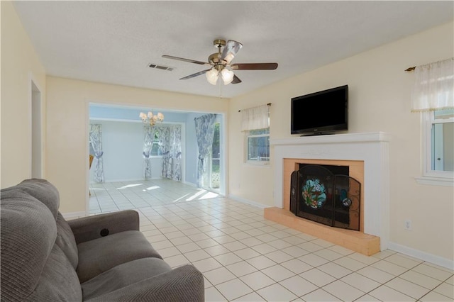 tiled living room with ceiling fan with notable chandelier