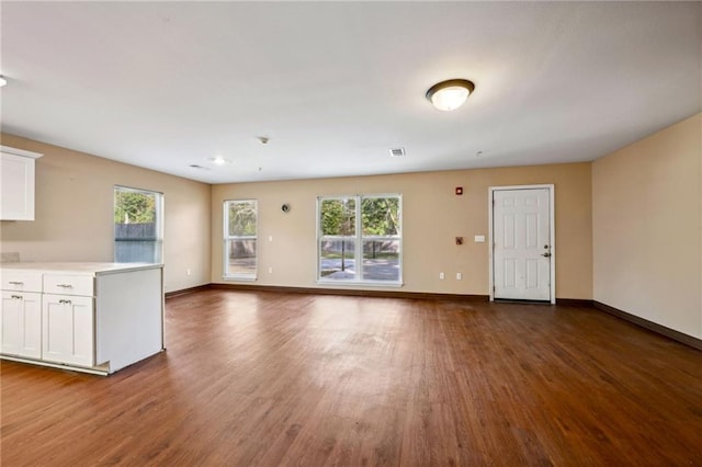 unfurnished living room featuring dark wood-type flooring and a wealth of natural light