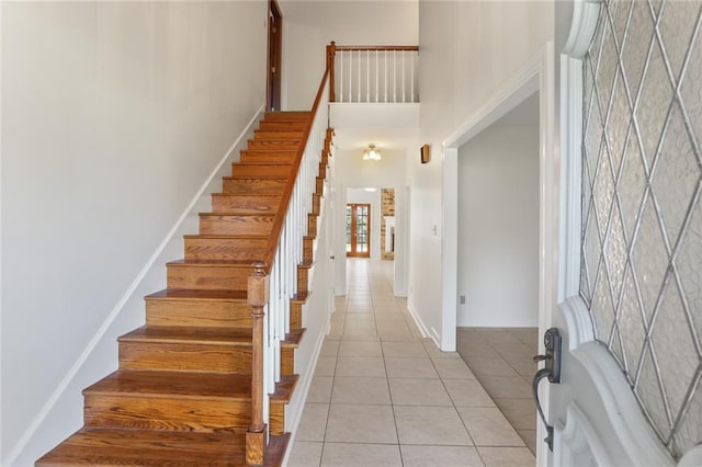 stairs with tile patterned floors and a high ceiling