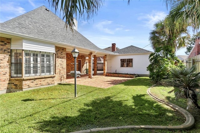 rear view of property featuring a patio area and a lawn