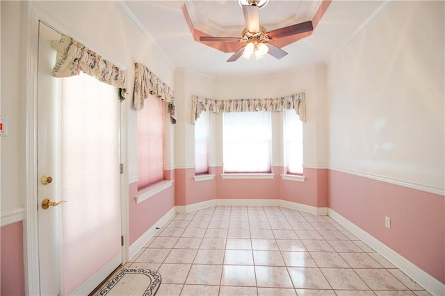 empty room featuring crown molding, ceiling fan, light tile patterned floors, and a raised ceiling