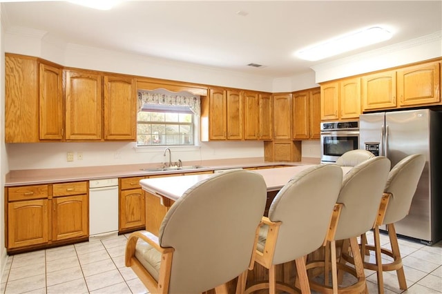 kitchen with light tile patterned floors, sink, a center island, stainless steel appliances, and a breakfast bar