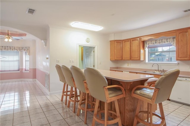 kitchen featuring sink, white dishwasher, ceiling fan, ornamental molding, and light tile patterned floors