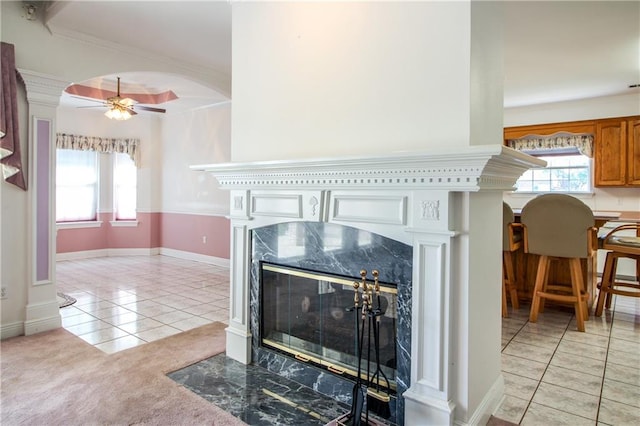 room details featuring a premium fireplace, ornamental molding, ceiling fan, and tile patterned flooring