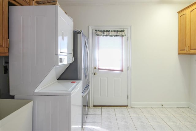 laundry room featuring cabinets, stacked washer / drying machine, and light tile patterned floors