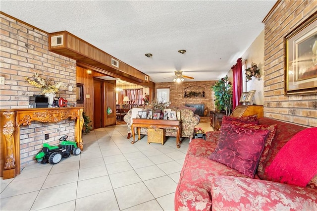 tiled living room with ceiling fan, a textured ceiling, wooden walls, and a fireplace