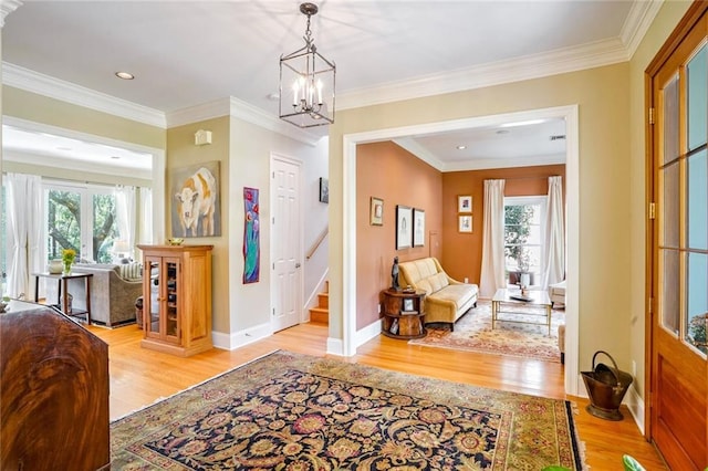 foyer featuring ornamental molding, a notable chandelier, and light wood-type flooring