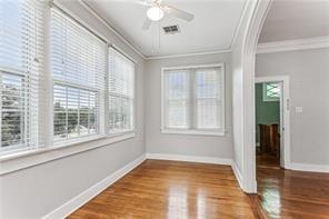 spare room featuring a wealth of natural light, ornamental molding, and hardwood / wood-style flooring