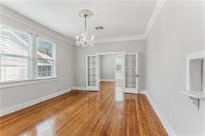 unfurnished dining area with a notable chandelier, wood-type flooring, and ornamental molding