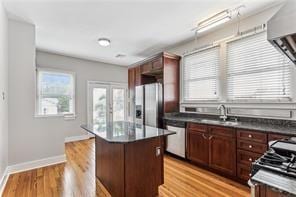 kitchen featuring stainless steel appliances, dark brown cabinetry, light wood-type flooring, and a kitchen island