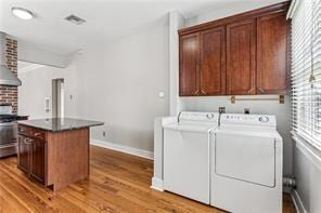 washroom with hardwood / wood-style floors, washer and dryer, and cabinets