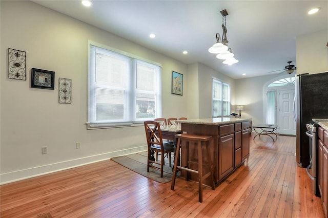 kitchen with a center island, light hardwood / wood-style flooring, ceiling fan, and a breakfast bar