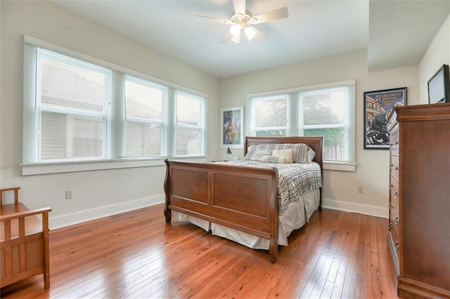 bedroom featuring ceiling fan, hardwood / wood-style flooring, and multiple windows