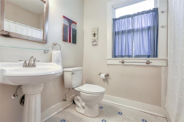 bathroom featuring toilet, sink, and tile patterned flooring