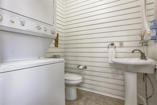 561214 Woodlawn Pl, New Orleans, LA 70124 - bathroom featuring estacked washer and dryer, tile patterned flooring, and toilet