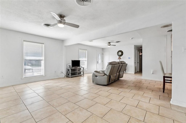 1005 35 Th St, Gretna, LA 70053 - living room featuring a ceiling fan, a textured ceiling, visible vents, light tile patterned floors, and baseboards