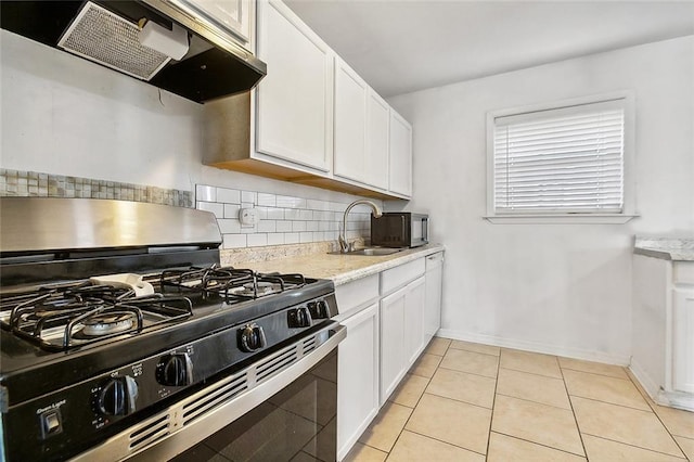 kitchen featuring exhaust hood, light tile patterned floors, white cabinetry, gas range, and sink