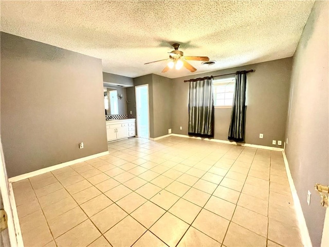 tiled empty room featuring a textured ceiling and ceiling fan