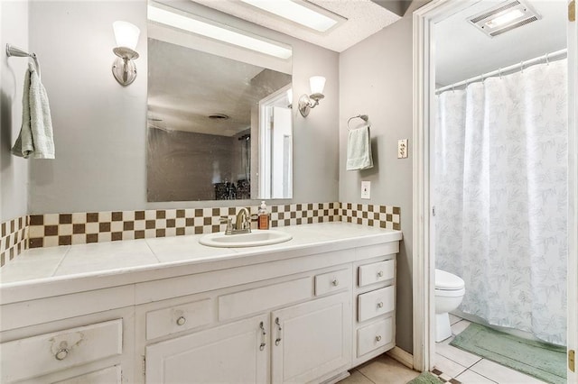 bathroom featuring tile patterned floors, decorative backsplash, vanity, and toilet