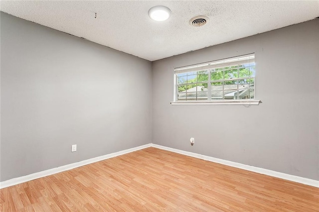 spare room featuring a textured ceiling and light wood-type flooring