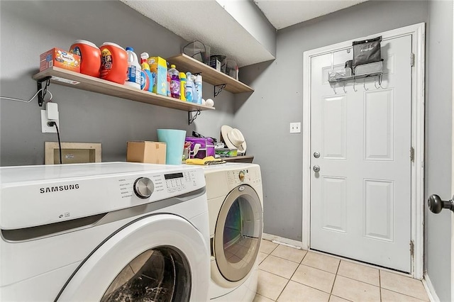 laundry room featuring washing machine and clothes dryer and light tile patterned flooring