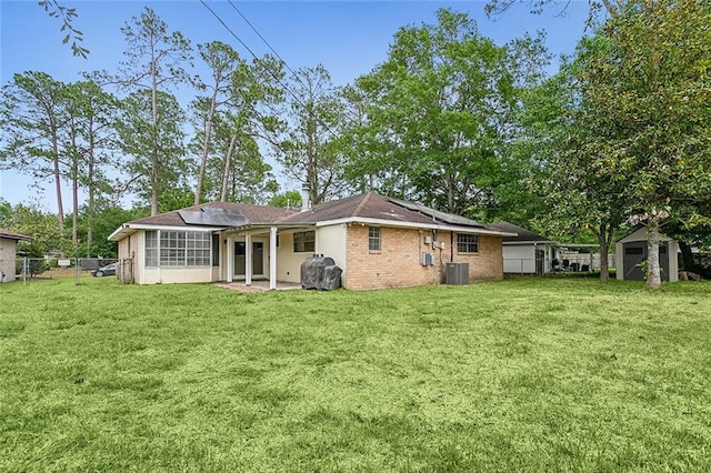 rear view of property featuring solar panels, a yard, a shed, and central air condition unit