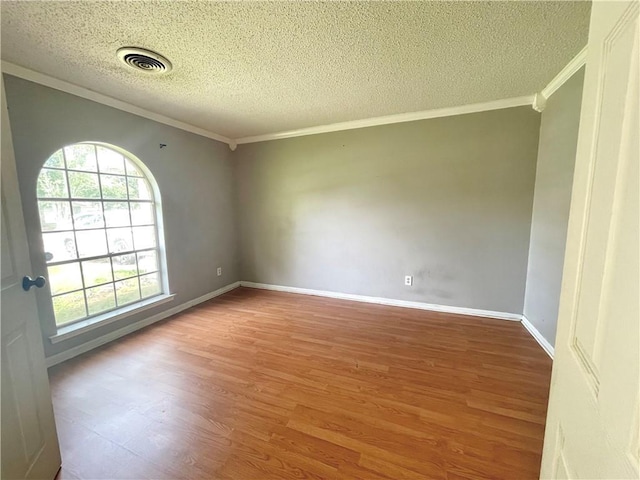 empty room with a textured ceiling, light hardwood / wood-style floors, and crown molding