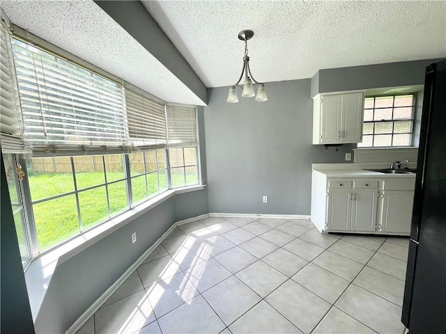 kitchen featuring a wealth of natural light, white cabinets, and hanging light fixtures