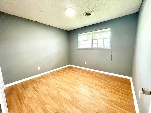 empty room with light hardwood / wood-style floors and a textured ceiling