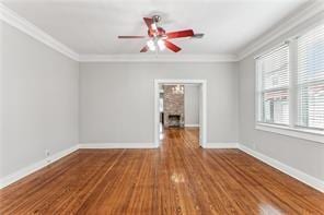 5612 Woodlawn Pl, New Orleans, LA 70124 - unfurnished room featuring ornamental molding, a ceiling fan, wood finished floors, baseboards, and a fireplace