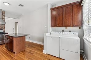 5612 Woodlawn Pl, New Orleans, LA 70124 - laundry area featuring washing machine and dryer, wood finished floors, cabinet space, and baseboards