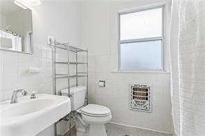 5612 Woodlawn Pl, New Orleans, LA 70124 - full bathroom featuring tile walls, toilet, a sink, and a shower with shower curtain