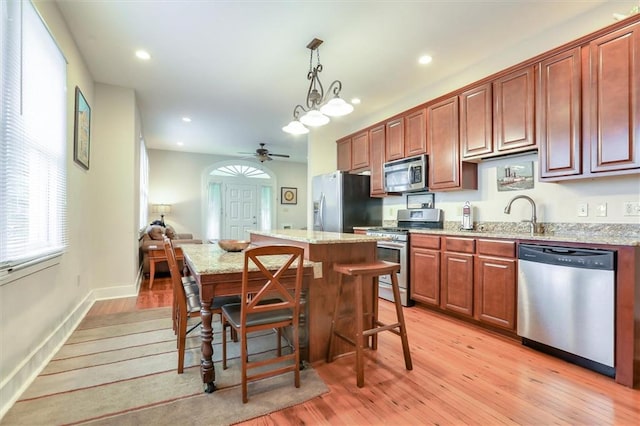 5612 Woodlawn Pl, New Orleans, LA 70124 - kitchen with appliances with stainless steel finishes, light wood-style floors, ceiling fan, pendant lighting, and light stone counters