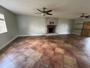 unfurnished living room featuring ceiling fan and a fireplace