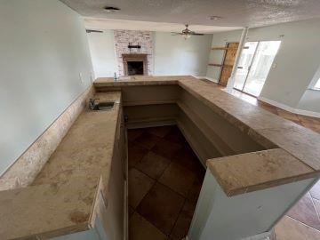 kitchen featuring ceiling fan, light tile patterned floors, kitchen peninsula, and a fireplace