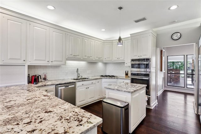 kitchen with hanging light fixtures, stainless steel appliances, sink, light stone countertops, and white cabinetry