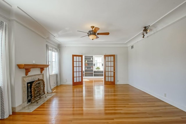 unfurnished living room with ceiling fan, french doors, a healthy amount of sunlight, and light hardwood / wood-style floors