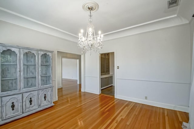 unfurnished dining area featuring an inviting chandelier and hardwood / wood-style flooring