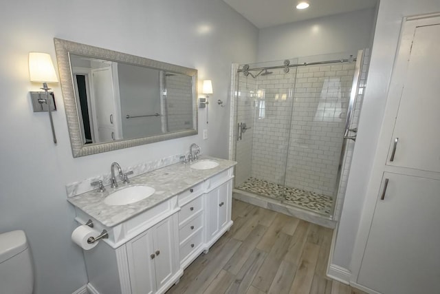 bathroom featuring vanity, hardwood / wood-style flooring, toilet, and a shower with shower door